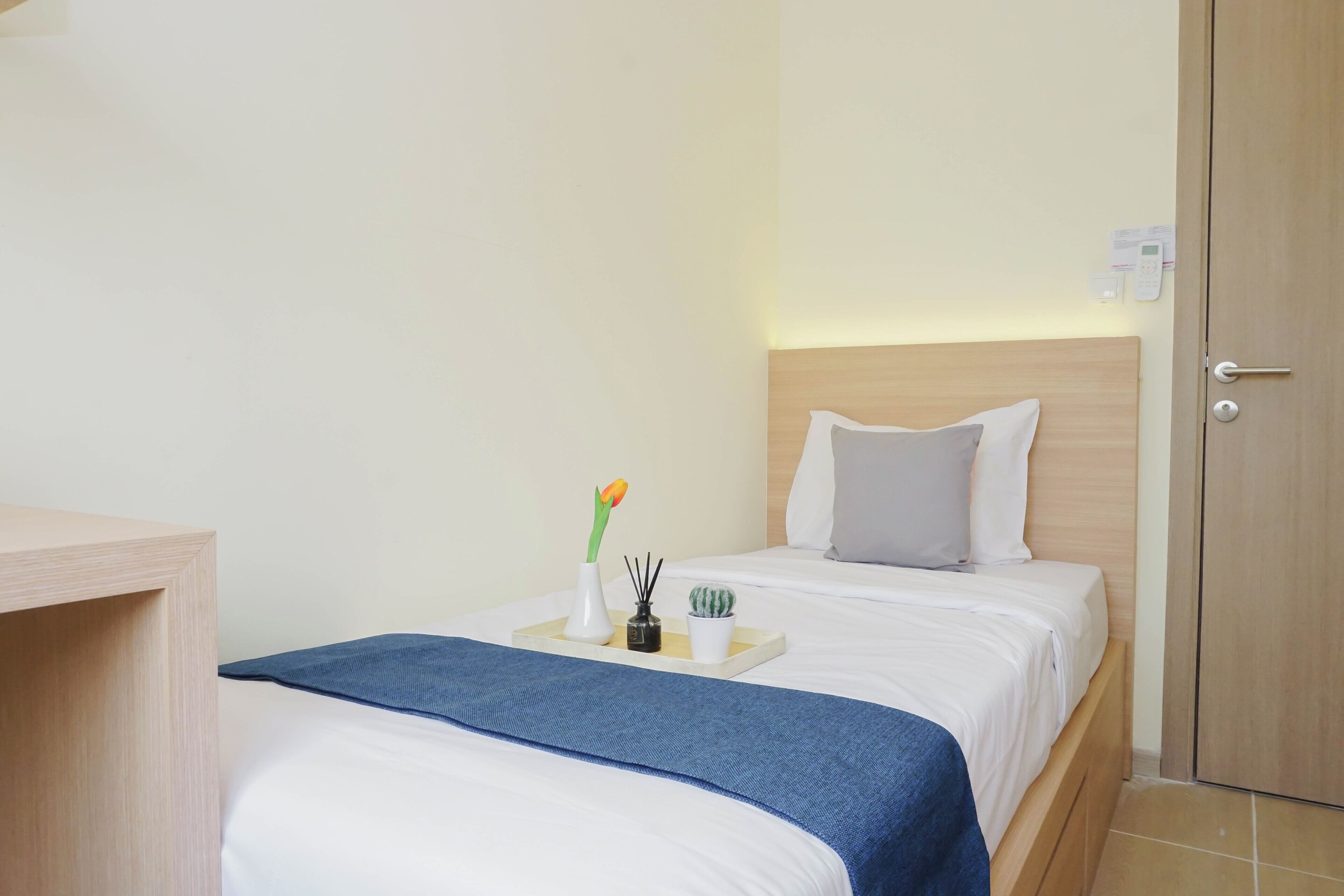 A hotel room with a bed, bedside table, and a wooden wardrobe.