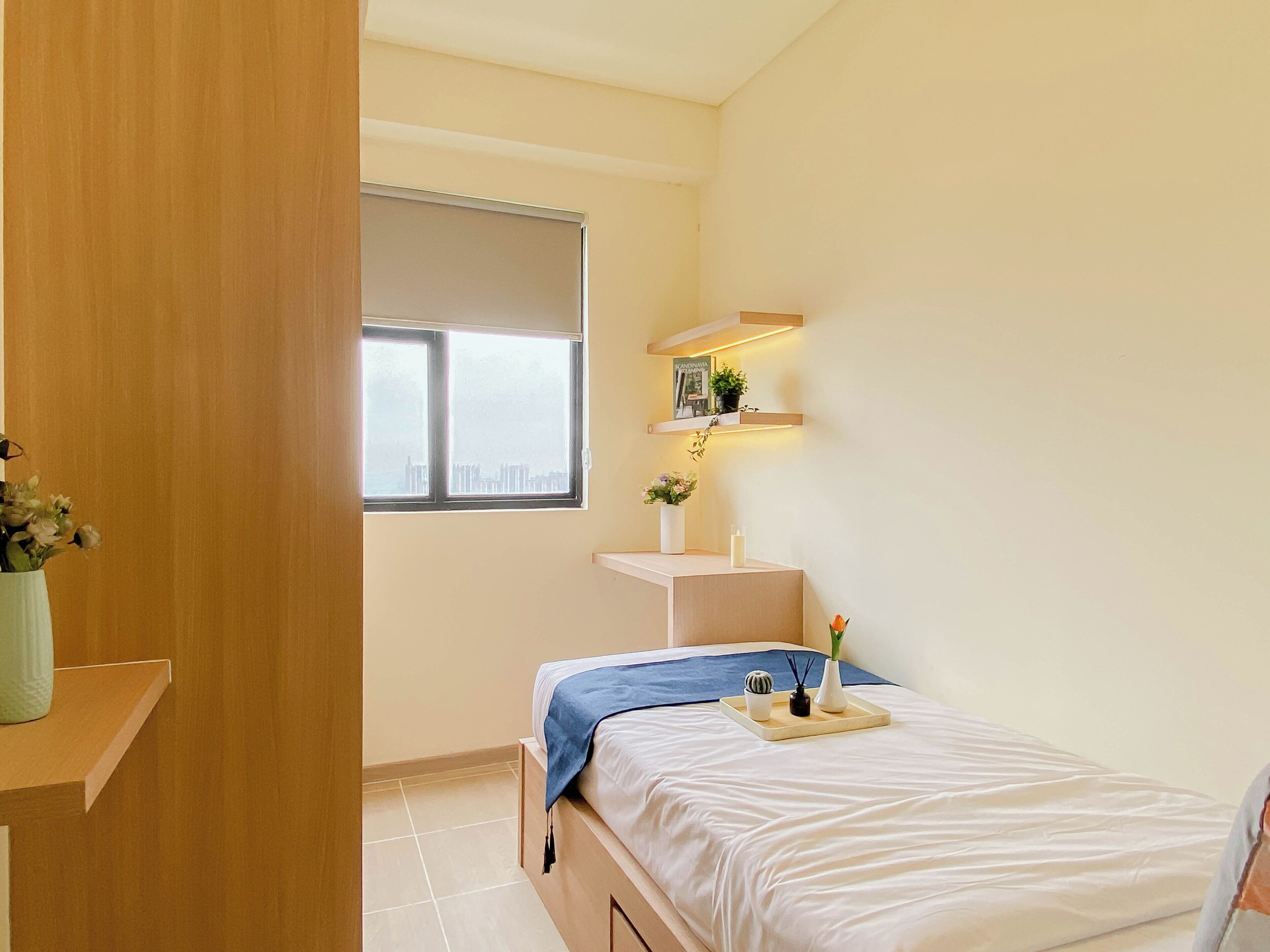 Ein Schlafzimmer mit Bett, Fenster, Ablagefläche mit Pflanze und Vase.