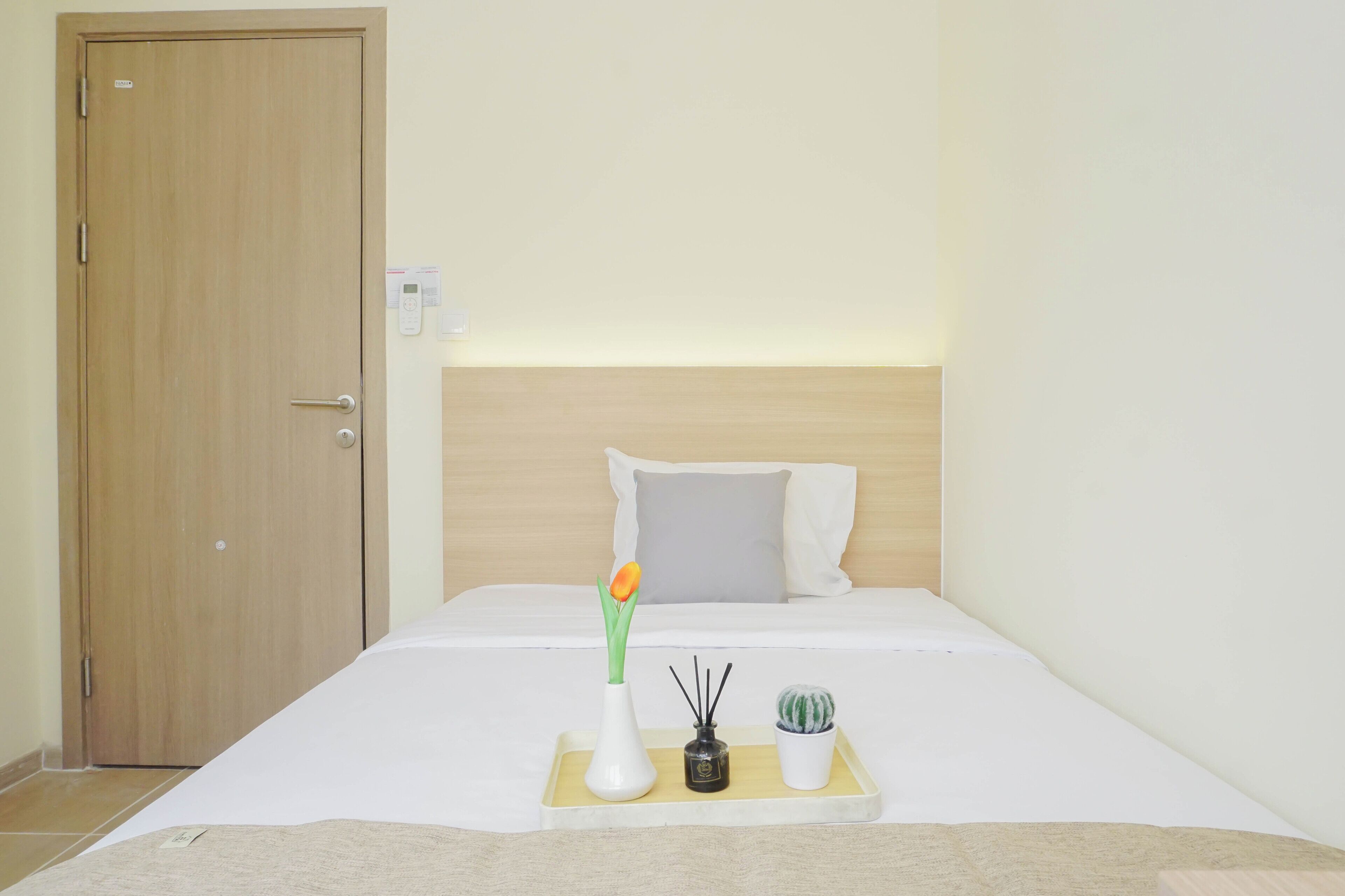 Ein Hotelzimmer mit einem Bett, einem Nachttisch mit Vase, Kerze und einer kleinen Pflanze.