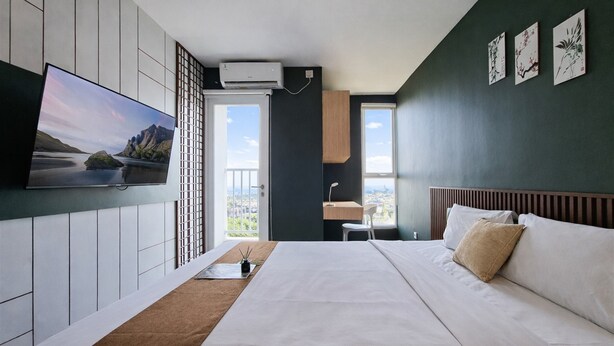 Ein modernes Hotelzimmer mit einem großen Bett, einem Flachbildfernseher, einem Schreibtisch und Blick auf die Stadt.