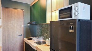 Eine kompakte Küche mit einem schwarzen Kühlschrank, einer Mikrowelle und einem Spülbecken.