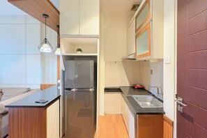 A compact kitchen with a refrigerator, a sink, and a countertop. - Cozy Stay 2Br Apartment At Malioboro City (Depok)
