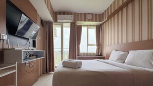 Habitación de hotel con cama, televisión, aire acondicionado y ventana con cortinas.