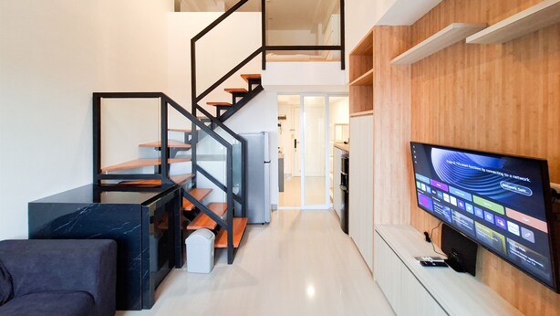 A modern living space with a staircase, a flat-screen TV, and a minimalist design. - Minimalist Studio Loft Apartment At Kingland Avenue (South Tangerang)