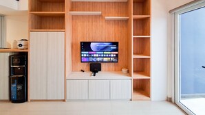 A modern room with a built-in TV, wooden shelving, and a water dispenser. - Minimalist Studio Loft Apartment At Kingland Avenue (South Tangerang)