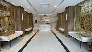 A hotel lobby with a reception desk, two seating areas, and a marble floor. - Minimalist Studio Loft Apartment At Kingland Avenue (South Tangerang)