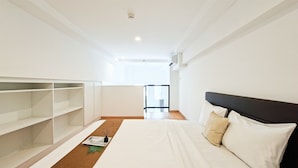 A modern hotel room with a large bed, built-in shelving, and a view of the city. - Affordable Price Studio Loft At Kingland Avenue Apartment (South Tangerang)