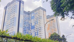 A multi-story residential building with a modern architectural design, featuring a grid of windows and balconies. - Cozy Studio Apartment At Urbantown Serpong (South Tangerang)