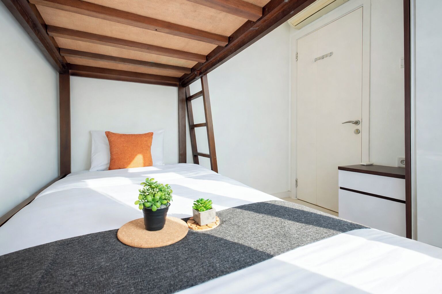 Une chambre à coucher avec un lit, un plafond en bois, une porte blanche et un petit meuble.