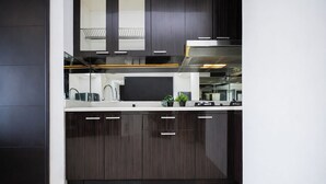 Una cocina moderna con armarios de madera oscura, encimeras blancas, una campana extractora de acero inoxidable y una pequeña maceta sobre la encimera.