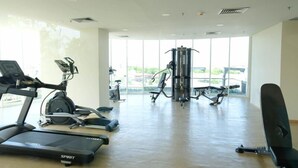 A gym with treadmills, elliptical machines, and a weight machine. - Comfy Modern Look Studio Room At Apartment Grand Dharmahusada Lagoon (Surabaya)