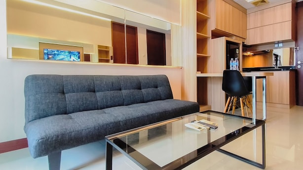 Una sala de estar moderna con un sofá gris, una mesa de centro de vidrio y un televisor montado en la pared.