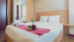 Una cama bien hecha con sábanas blancas, un plaid rosa y dos macetas con plantas.