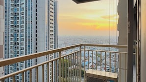 Ein Hochhaus mit einem Balkon und Blick auf die Stadt bei Sonnenuntergang.