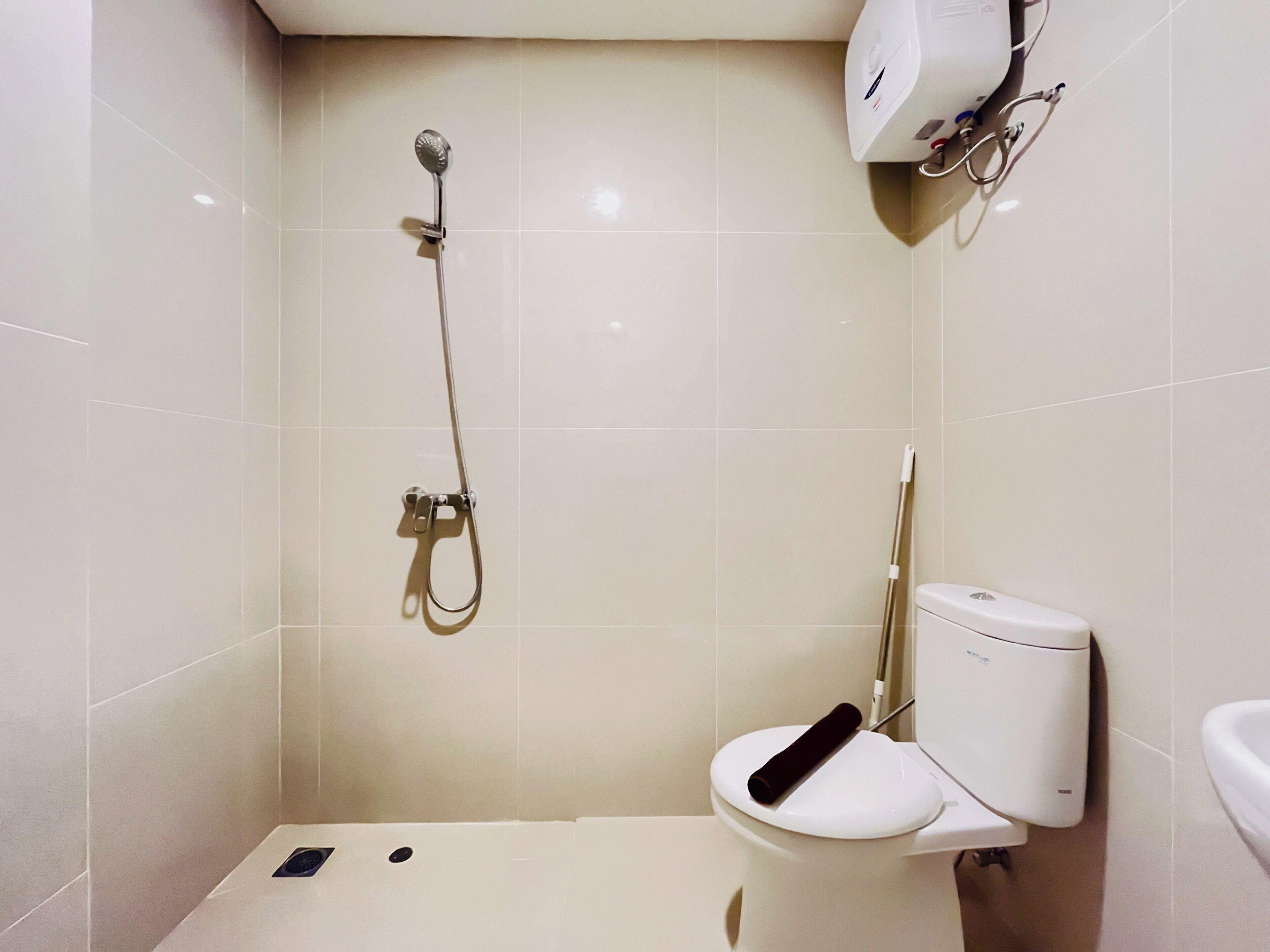 A bathroom with a toilet, a shower, and a hand dryer.