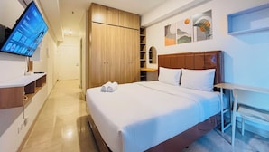 Ein Hotelzimmer mit Bett, Fernseher, Kleiderschrank und Bildern an der Wand.