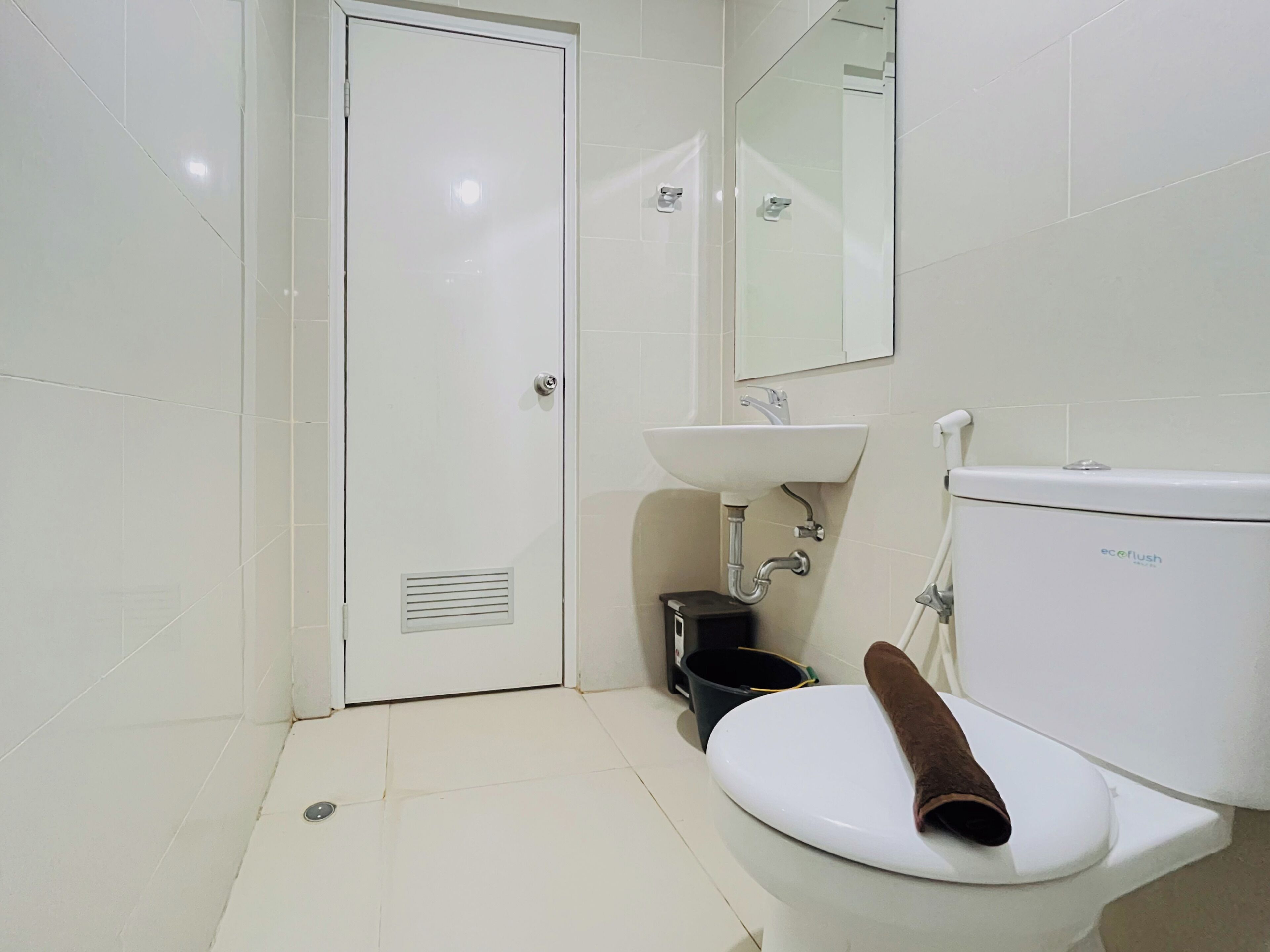 A bathroom with a toilet, sink, and a mirror.