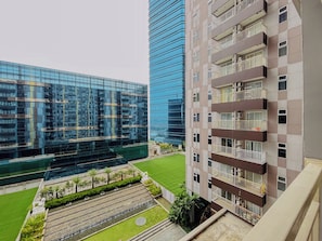 Un moderno edificio de gran altura con fachada de vidrio, un patio con fuente de agua y un edificio más pequeño con balcones.