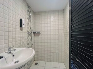 Ein Badezimmer mit einem weißen Waschbecken, einer Dusche mit Duschbrause und einer Toilette.