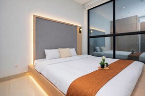 Una habitación de hotel moderna con una cama grande, una mesita de noche, una ventana y vistas a la ciudad.