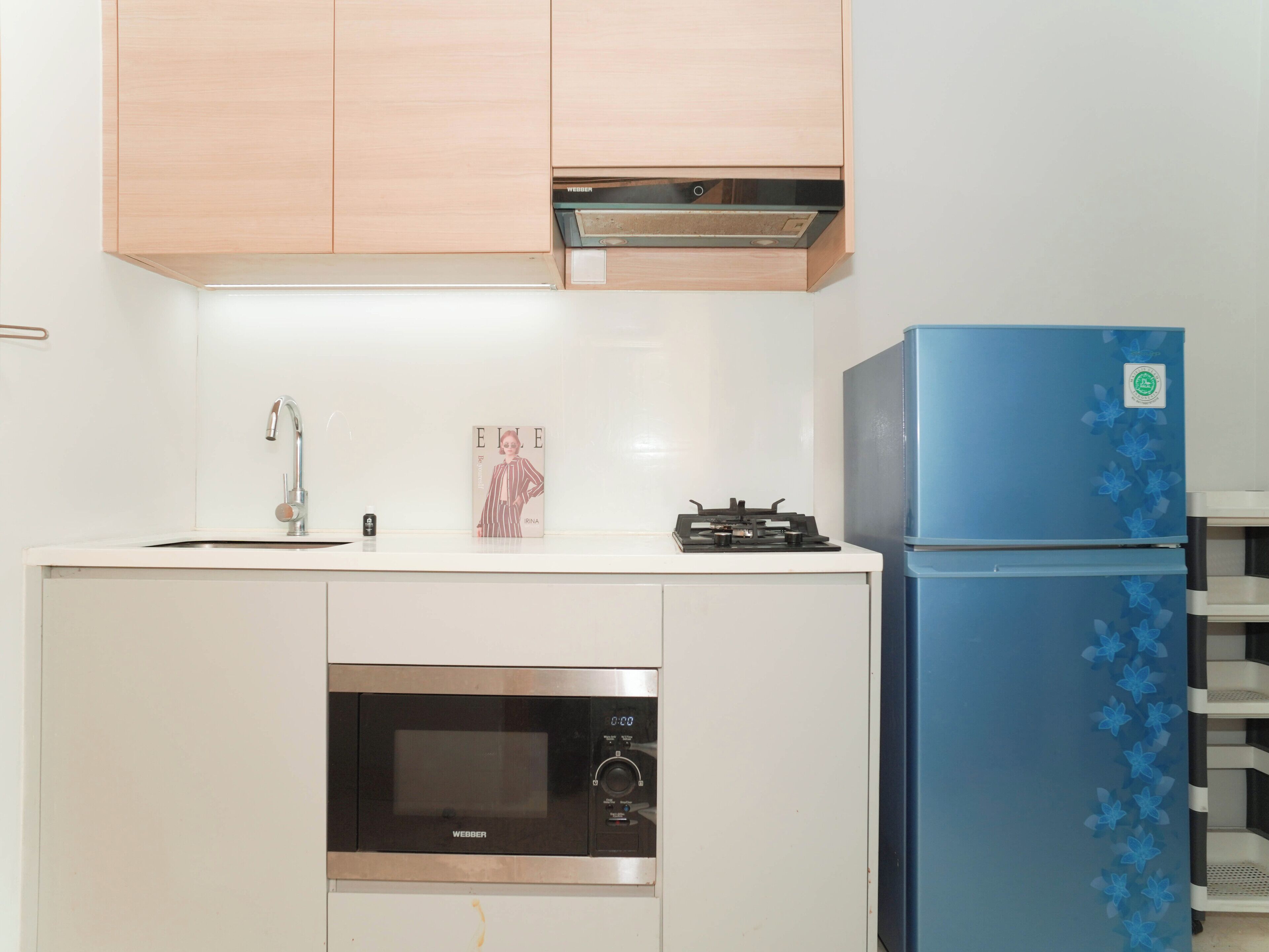 A compact kitchen with a microwave, stove, and blue refrigerator.