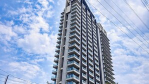 A high-rise building with multiple balconies, a clear sky, and visible power lines. - Chic And Warm Studio With Super King Bed At Capitol Suites Apartment (Jakarta)