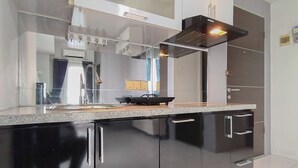 Una cocina moderna con armarios negros, encimera de granito y campana extractora de acero inoxidable.