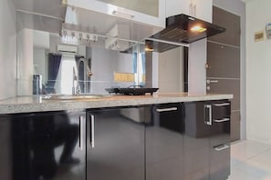 A modern kitchen with black cabinets, a granite countertop, and a stainless steel range hood. - Spacious And Cozy 2Br At Tamansari Prospero Sidoarjo Apartment (Sidoarjo)