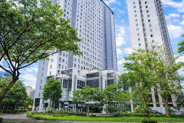A modern apartment building with a central courtyard, surrounded by greenery and adjacent high-rise buildings. - Spacious And Cozy 2Br At Tamansari Prospero Sidoarjo Apartment (Sidoarjo)