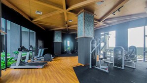 A gym with treadmills, weight machines, and a wooden floor. - Chic Brown Touch Studio At Apartment Collins Boulevard (Tangerang)