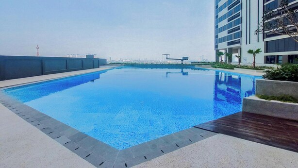 A rooftop swimming pool with a clear view of the city skyline in the background. - Chic Brown Touch Studio At Apartment Collins Boulevard (Tangerang)