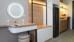 A modern kitchen with a built-in refrigerator, a round mirror, and a wooden countertop. - Chic Brown Touch Studio At Apartment Collins Boulevard (Tangerang)