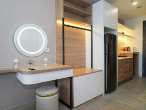 A modern kitchen with a built-in refrigerator, a round mirror, and a wooden countertop. - Chic Brown Touch Studio At Apartment Collins Boulevard (Tangerang)