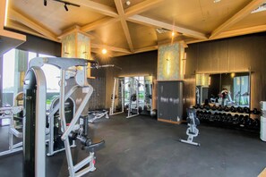 A gym with weightlifting equipment, cardio machines, and a mirror wall. - Bright And Relaxing 2Br At Collins Boulevard Apartment (Tangerang)