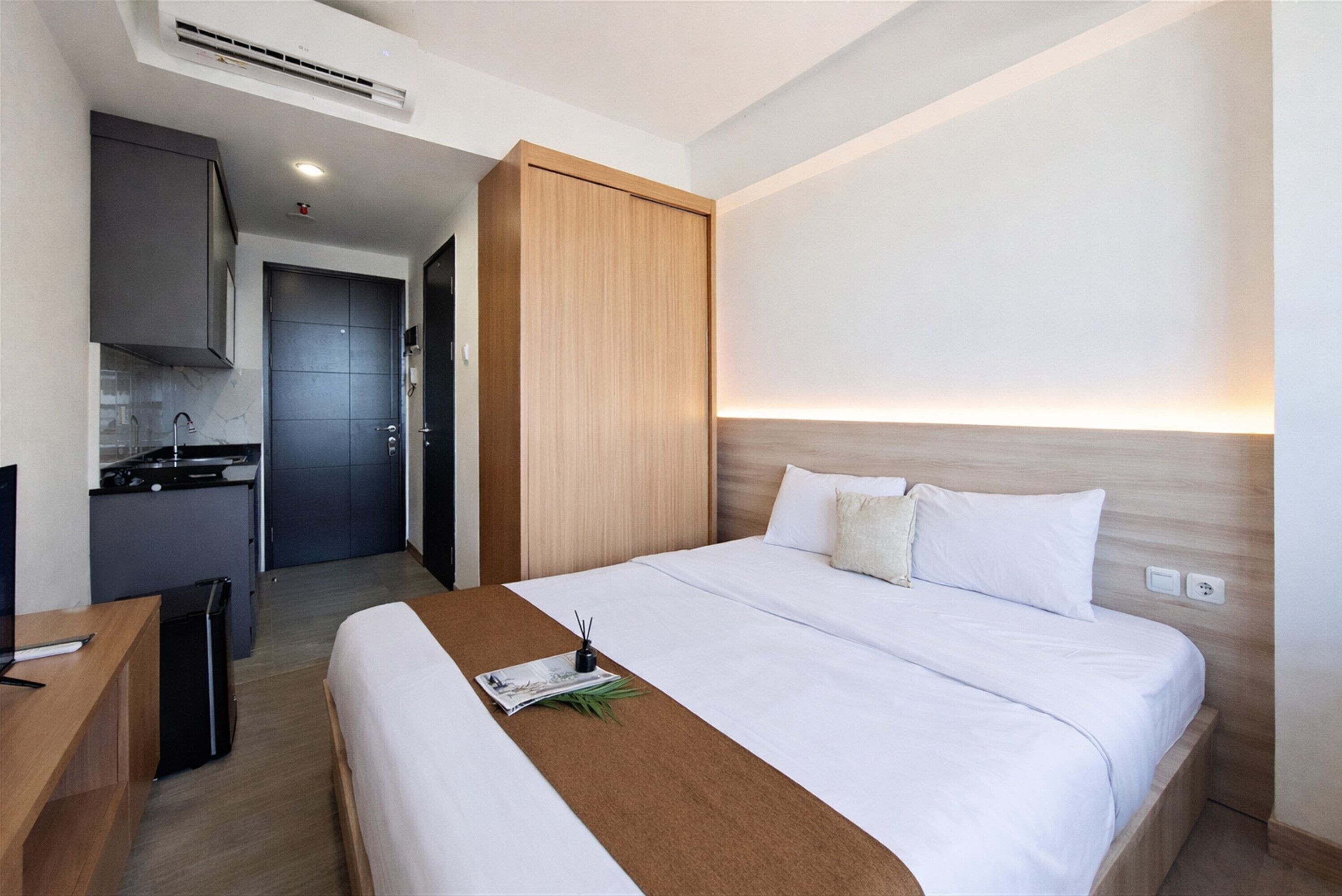 Une chambre d’hôtel comprenant un lit, un bureau, une kitchenette et une armoire.