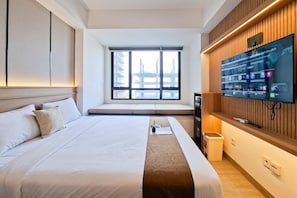 Ein Hotelzimmer mit einem großen Bett, einem an der Wand montierten Fernseher, einem Fenster mit Blick auf eine Brücke und einer Wandverkleidung aus Holz.