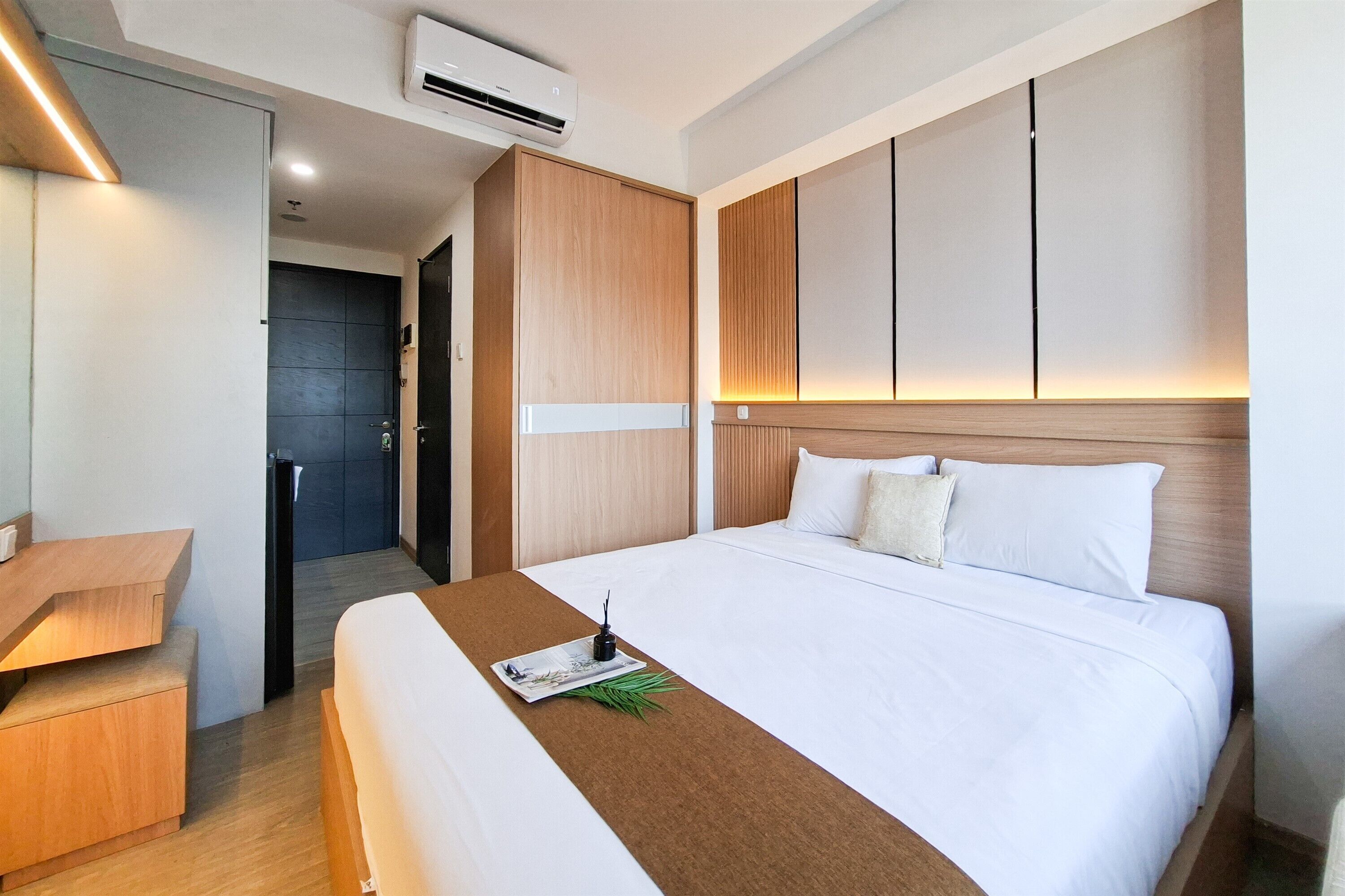 A hotel room with a bed, a desk, and a wardrobe.