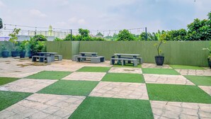 A rooftop patio with checkered flooring, outdoor seating, and string lights. - Classic Red Studio At Nifarro Park Apartment (Jakarta)