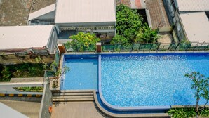 An aerial view of a swimming pool surrounded by buildings, with a clear sky above. - Classic Red Studio At Nifarro Park Apartment (Jakarta)