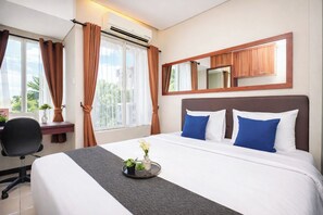 Ein Hotelzimmer mit Bett, Schreibtisch, Klimaanlage, Spiegel und einem Vorhangfenster.