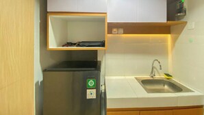 Μια κουζίνα με εντοιχισμένο ψυγείο, έναν νεροχύτη και έν α ράφι πάνω από το ψυγείο.