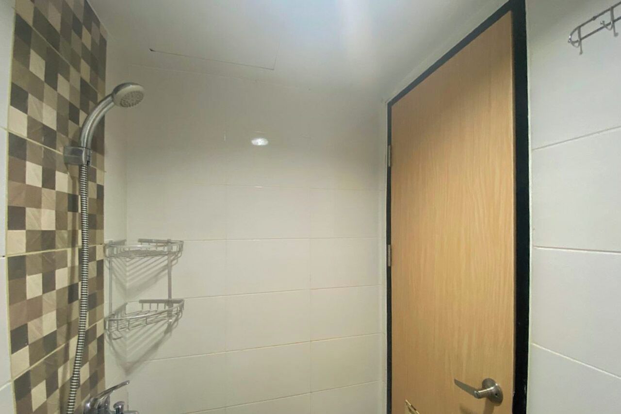 A bathroom with a shower, a wooden door, and a tiled wall.