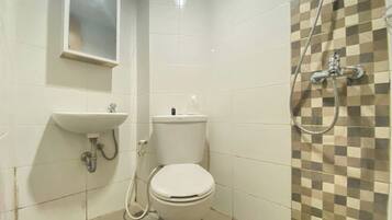 A small bathroom with a toilet, sink, and shower.