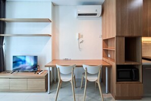 Una kitchenette moderna con un microondas, un refrigerador pequeño y un mueble de madera.
