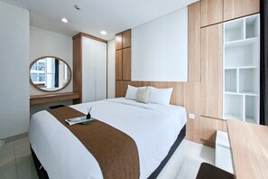 Una habitación de hotel moderna con una cama grande, un espejo redondo, un armario de madera y un escritorio con una silla.