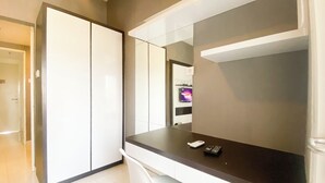 Ein modernes Hotelzimmer mit Schreibtisch, Stuhl, Kleiderschrank und Fernseher.