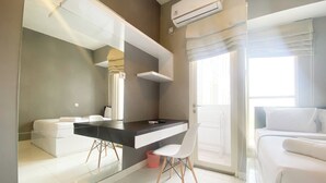 Ein modernes Hotelzimmer mit einem großen Spiegel, einer schwarzen Ablagefläche, einem weißen Stuhl, einem Bett und einer Klimaanlage.