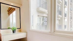 A bathroom with a mirror, a potted plant, a red stool, and a window with a view of balconies. - Practical 2Br For 4 Pax At Podomoro Golf View Apartment (Gunung Putri)