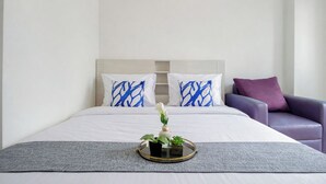 A hotel room with a bed, a chair, and a tray with plants. - Classic White Studio At Apartment Woodland Park Residence (Jakarta)