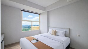 A hotel room with a large bed, a window with a view, a bedside table, and a nightstand. - Cozy Living 1Br Apartment At Silkwood Residence (Tangerang)